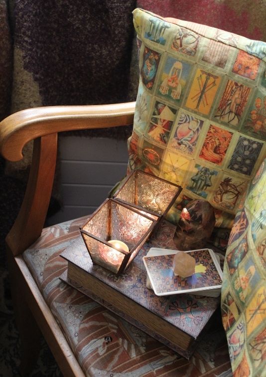 tarot cards, candles and a book on chair