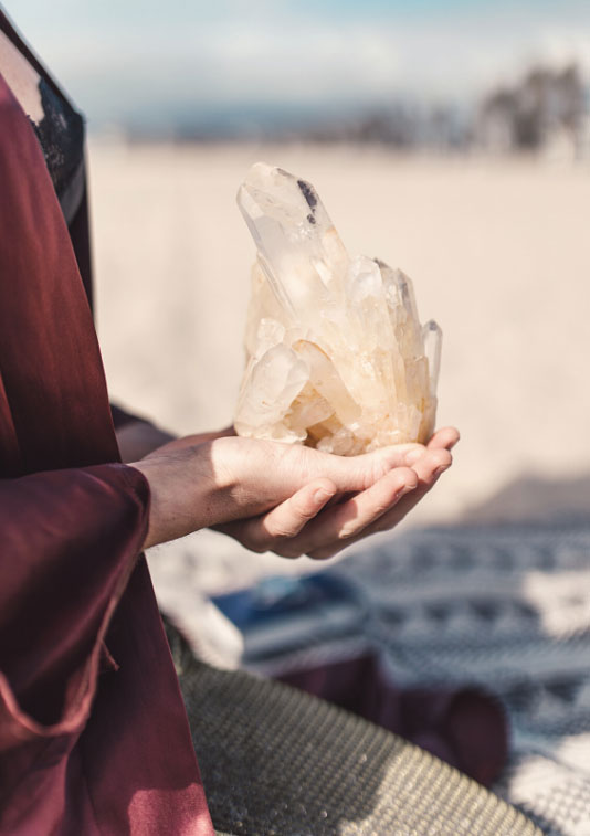 a photo of a person holding a crsystal on the beach
